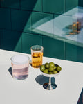 HAY Italian Ice Cup, Stainless Steel, stainless steel ice cream cup, filled with green olives beside two clear glasses on a white counter