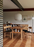 Mogensen 3171 oak bench with black leather seat shown with J39 upholstered chairs in a modern Danish dining room