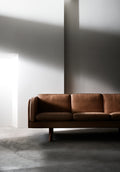 JG Sofa 3 seater in natural leather on wood legs in a minimalist interior with dramatic light, Scandinavian modern