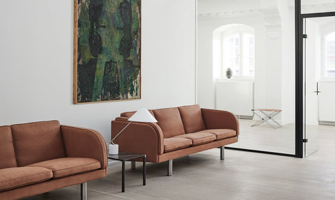 Two terracotta JG Sofas in a modern office lounge with minimalist side table