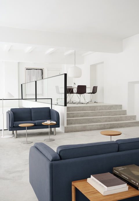 Blue JG Sofas in a Scandinavian office lounge with round side tables and glass railing