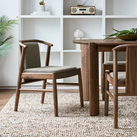 Gus* Modern Lanark Dining Chair in Classic Walnut with Lundy Truffle fabric at round dining table with white shelving background