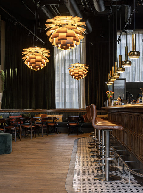Restaurant and bar interior with multiple Louis Poulsen PH Artichoke pendants in a warm metallic finish creating ambient lighting
