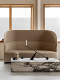 Audo Copenhagen Tearoom Sofa, High Back, Tearoom Sofa, High Back with US Power Outlet in beige, set against a window with a marble coffee table