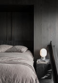 white marble table lamp on marble plinth end table in a scandinavian moody bedroom