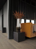 large echasse vase in smoked glass on brushed metal base sitting on top of a marble block end table by audo copenhagen