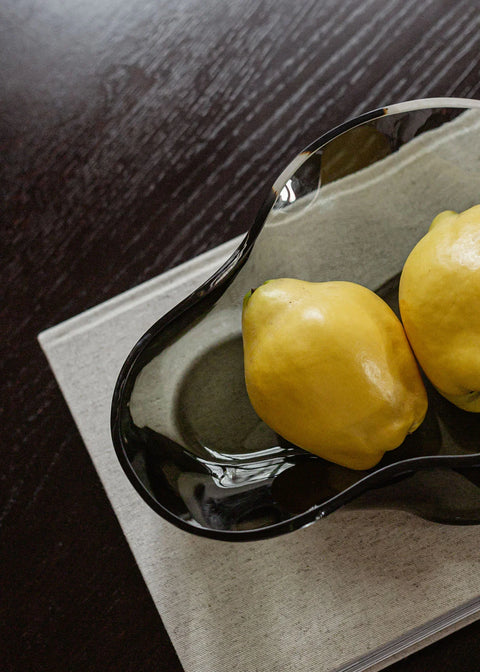 Tinted glass scandinavian bowl holding fruit on a table