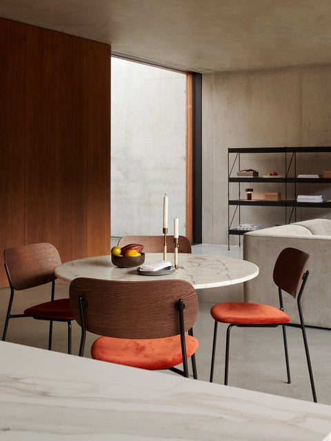 Audo Copenhagen Co Dining Chairs with orange seats around a white marble Column Table. A black Zet shelf is in the back