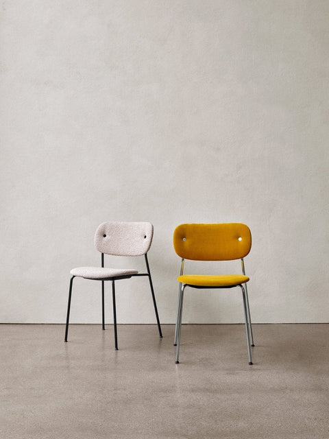 Audo Copenhagen Co Dining Chair, Without Arms, Fully Upholstered, fully upholstered Co Dining Chairs. One in off-white bouclé with a black frame, one in yellow with a chrome frame