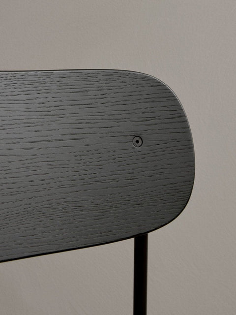Audo Copenhagen Co Bar Chair, Non-Upholstered, close-up view of the Co Bar Chair's backrest in black stained oak veneer, highlighting the rich wood grain and screw