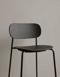 Audo Copenhagen Co Counter Chair, Non-Upholstered. A close-up of the black stained oak veneer seat and backrest on a black steel frame