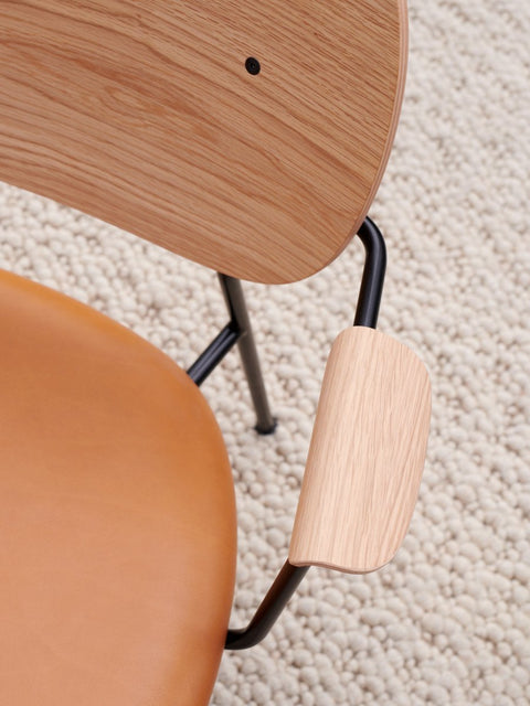 Audo Copenhagen Co Lounge Chair, Partially Upholstered, overhead detail shot of the Co Lounge Chair showing the oak backrest, tan leather seat, and black frame on a cream wool rug