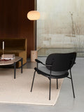 Audo Copenhagen Co Lounge Chair, Partially Upholstered, black Co Lounge Chair on a cream rug in a modern living room, with a brown sofa, coffee table, and floor lamp nearby