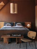 Audo Copenhagen Co Lounge Chair, Fully Upholstered, Co Lounge Chair with black frame and yellow upholstery in a bedroom with an Androgyne Lounge Table and Torso table lamp