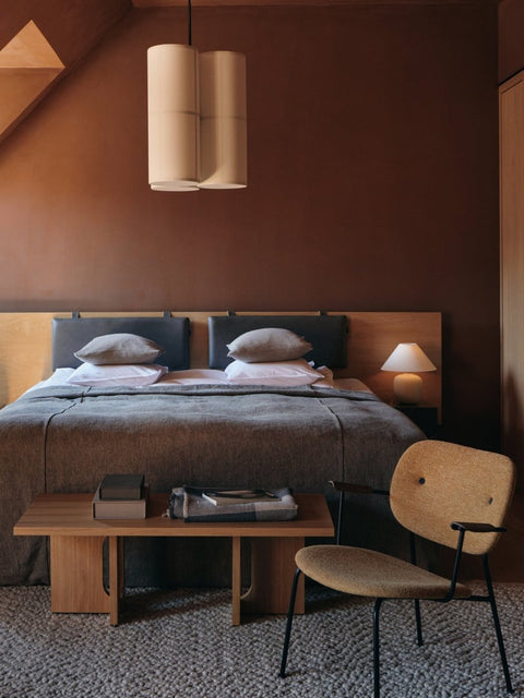 Audo Copenhagen Co Lounge Chair, Fully Upholstered, Co Lounge Chair with black frame and yellow upholstery in a bedroom with an Androgyne Lounge Table and Torso table lamp