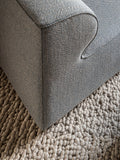 Corner detail of Eave Modular Sofa in grey fabric with curved armrest on wool rug