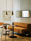 Audo Copenhagen Co Dining Chair, Non-Upholstered, dining corner with an orange Eave Dining Sofa, two Co Dining Chairs, a Column Table Lamp, and a Nimbus Mirror on the wall