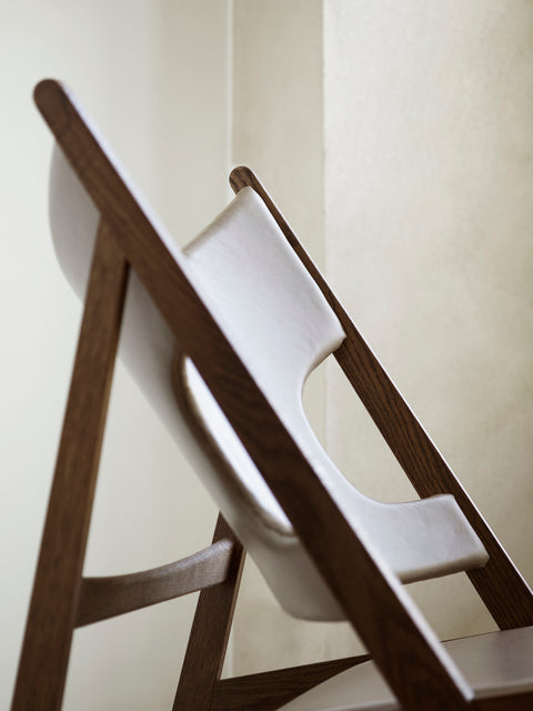 Detail view of Knitting Lounge Chair showing brown oak frame and smooth leather upholstery.