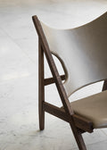 Knitting Lounge Chair in oak and leather with sculptural seat design on a marble floor.