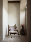 Knitting Lounge Chair with oak frame and leather seat in a minimalist corner interior with marble pedestal.