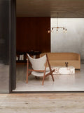 Audo Copenhagen Tearoom Chairs and Sofas, modern living room with a Knitting Chair, a Tearoom Sofa, and a marble Plinth coffee table under a chandelier