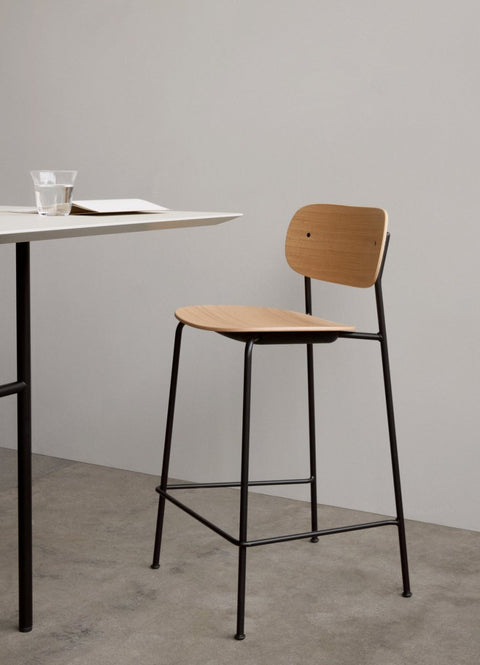 Audo Copenhagen Co Counter Chair, Non-Upholstered, Co Counter Chair in oak and black metal sits at a white Snaregade Counter Table with a Strandgade Drinking Glass on top