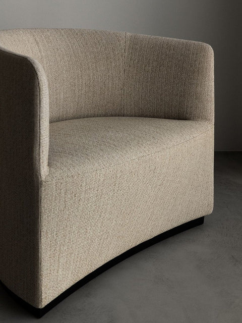 Audo Copenhagen Tearoom Chairs and Sofas, close-up shot of the Tearoom Lounge Chair, focusing on the light beige textured fabric of the curved arm and backrest