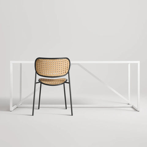 Made You Look Outdoor Chair by Blu Dot in Oblivion with plastic rattan seat and back, rear view with dining table