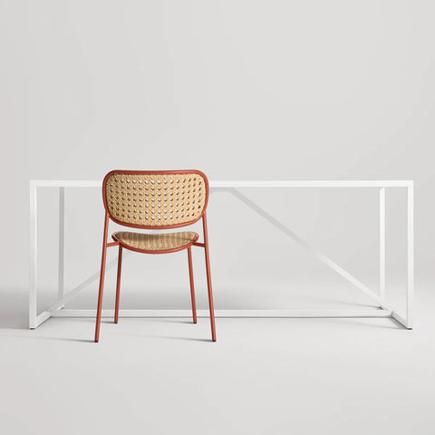 Made You Look Outdoor Chair by Blu Dot in Tomato with plastic rattan seat and back, rear view with dining table