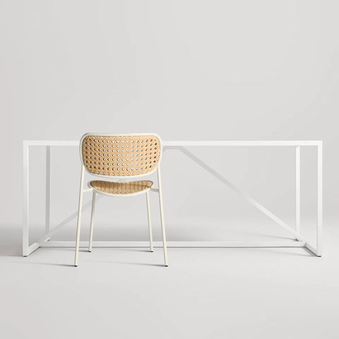 Made You Look Outdoor Chair by Blu Dot in White with plastic rattan seat and back, rear view with dining table