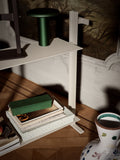 Detail of the Museum Trolley by String Furniture in white, holding a portable table lamp, books and boxes on its two aluminium shelves
