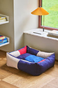 HAY Dog Bed Zip, Medium, Red, Blue, recycled polyester dog bed, on an oak floor by a window with a yellow pleated table lamp