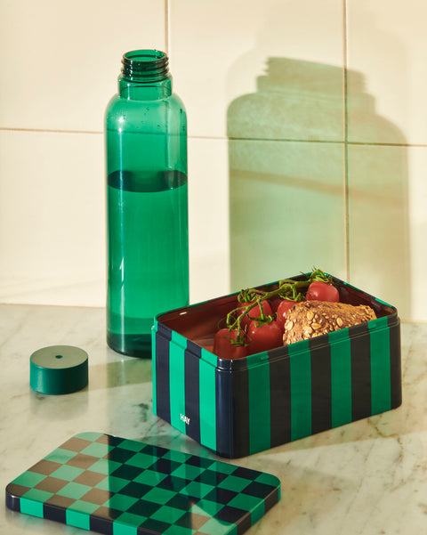 HAY Tin Container, Small, Green and Dark Blue, lidded tinplate storage tin, open on marble with tomatoes and bread beside a green water bottle