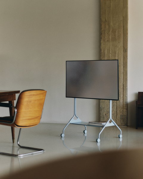 Pedestal Moon Tray Shelf in Powder Blue, steel tray shelf for a TV stand, fitted to a stand in a room beside a wooden chair