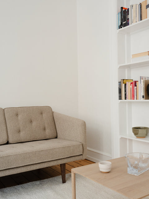 Close up of Borge Mogensen No. 1 Sofa in Barnum 3 boucle with smoked oak legs beside a Piloti coffee table in light oiled oak