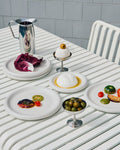 HAY Italian Ice Cup, Stainless Steel, stainless steel ice cream cup, two cups of olives and egg on a white slatted outdoor table with plates