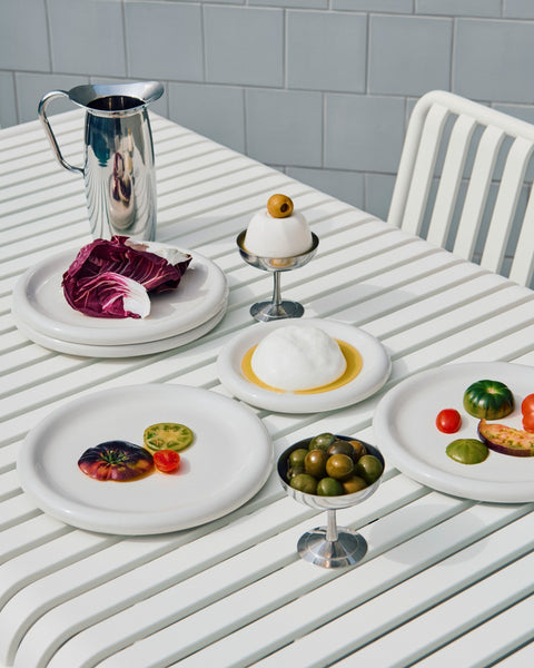 HAY Italian Ice Cup, Stainless Steel, stainless steel ice cream cup, two cups of olives and egg on a white slatted outdoor table with plates