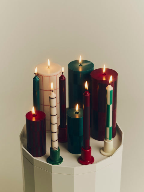 HAY Column Candle, Large, Red Grid Check, stearin pillar candles, a lit group in green, red and cream on a cream ribbed cabinet