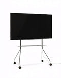 Pedestal Moon PRO TV Stand in Chrome, mobile rolling TV stand with shelf holding a flat screen TV, on a plain white background