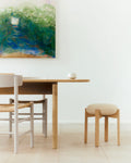 Stacked Fredericia Pioneer Stools in oak with neutral upholstered seats by window, J39 chair in background