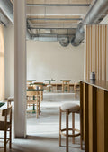 Minimalist cafe interior with oak Fredericia Pioneer counter stools and matching chairs in a Scandinavian modern dining space