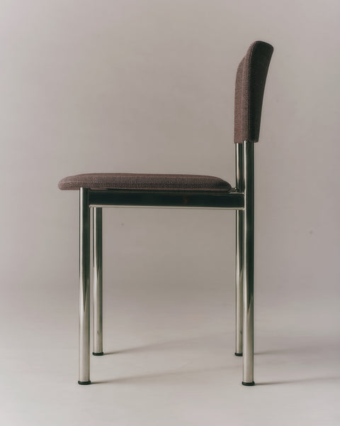 Side profile of Fredericia Plan Chair with dark fabric upholstery and brushed chrome legs