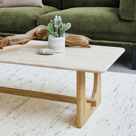Portico Rectangle Coffee Table by Gus Modern in white oak with travertine top, styled with cactus and driftwood décor on a light textured rug.