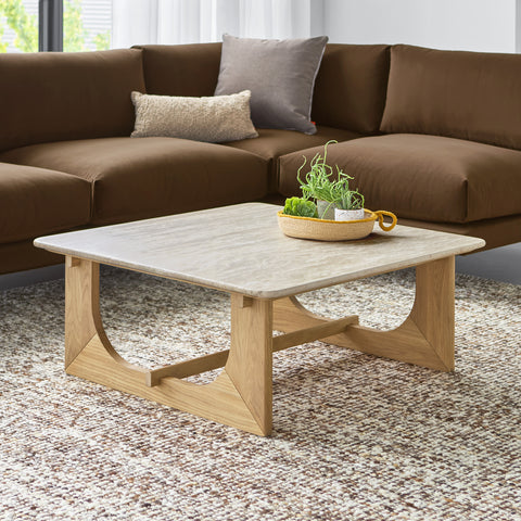 Portico Square Coffee Table by Gus Modern in white oak shown in a modern living room with travertine top and plush brown sectional.