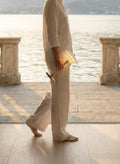 Woman in white linen carrying the lit Louis Poulsen PH 1/1 Portable lamp in brass across a lakeside terrace