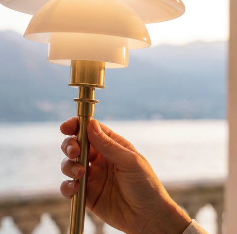 Close-up of the Louis Poulsen PH 1/1 Portable lamp in brass with opal glass shades held by a stone balustrade