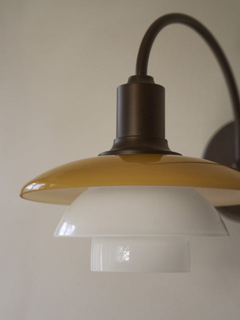 Close-up of the glossy amber and white opal shades of the unlit Louis Poulsen PH 2/2 Wall Lamp Centenary Edition