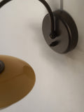 Close-up of the aged brass wall plate and curved arm of the Louis Poulsen PH 2/2 Wall Lamp Centenary Edition