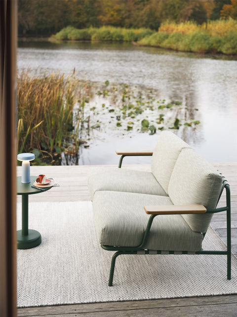 2 seater settle outdoor sofa by muuto on a deck by the water 