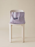 HAY Shopper Bag, Lavender, cotton tote bag, pale lilac shopper resting on a white wooden chair against a warm beige wall